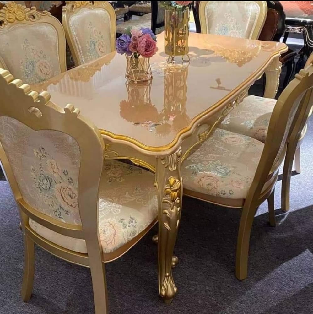 Ornate cream and gold dining table with coordinated upholstered chairs