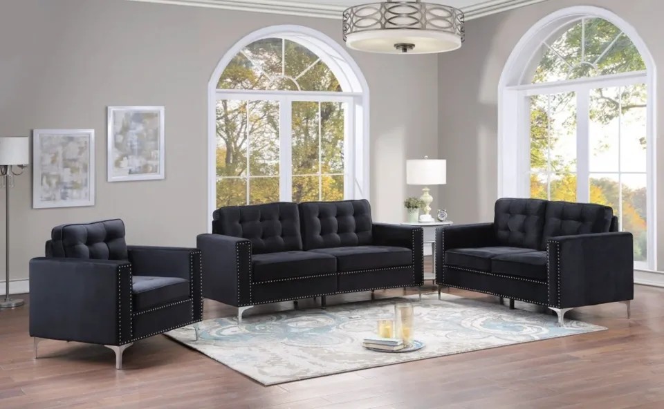 Black Chesterfield sofa and matching armchairs arranged in a bright living room